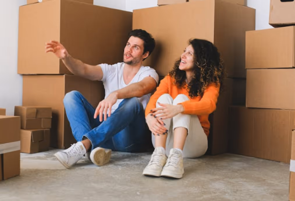 couple in a green flag relationship surrounded by moving boxes celebrating moving in together