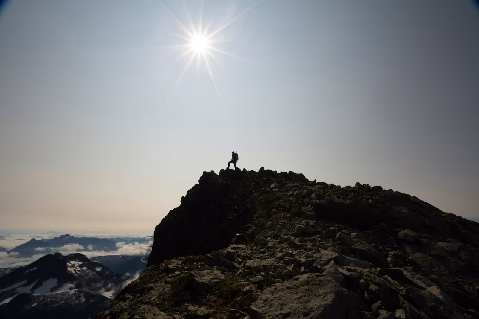 student standing at the peak of a mountain on a sunny day