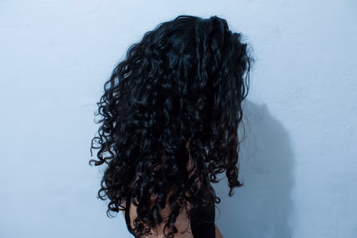 A side view of a woman with long curly black hair.