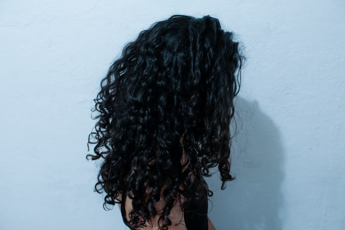 A side view of a woman with long curly black hair.