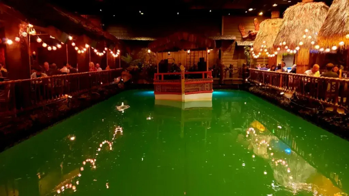 A bar interior with a large pool of water and a boat-shaped stage.