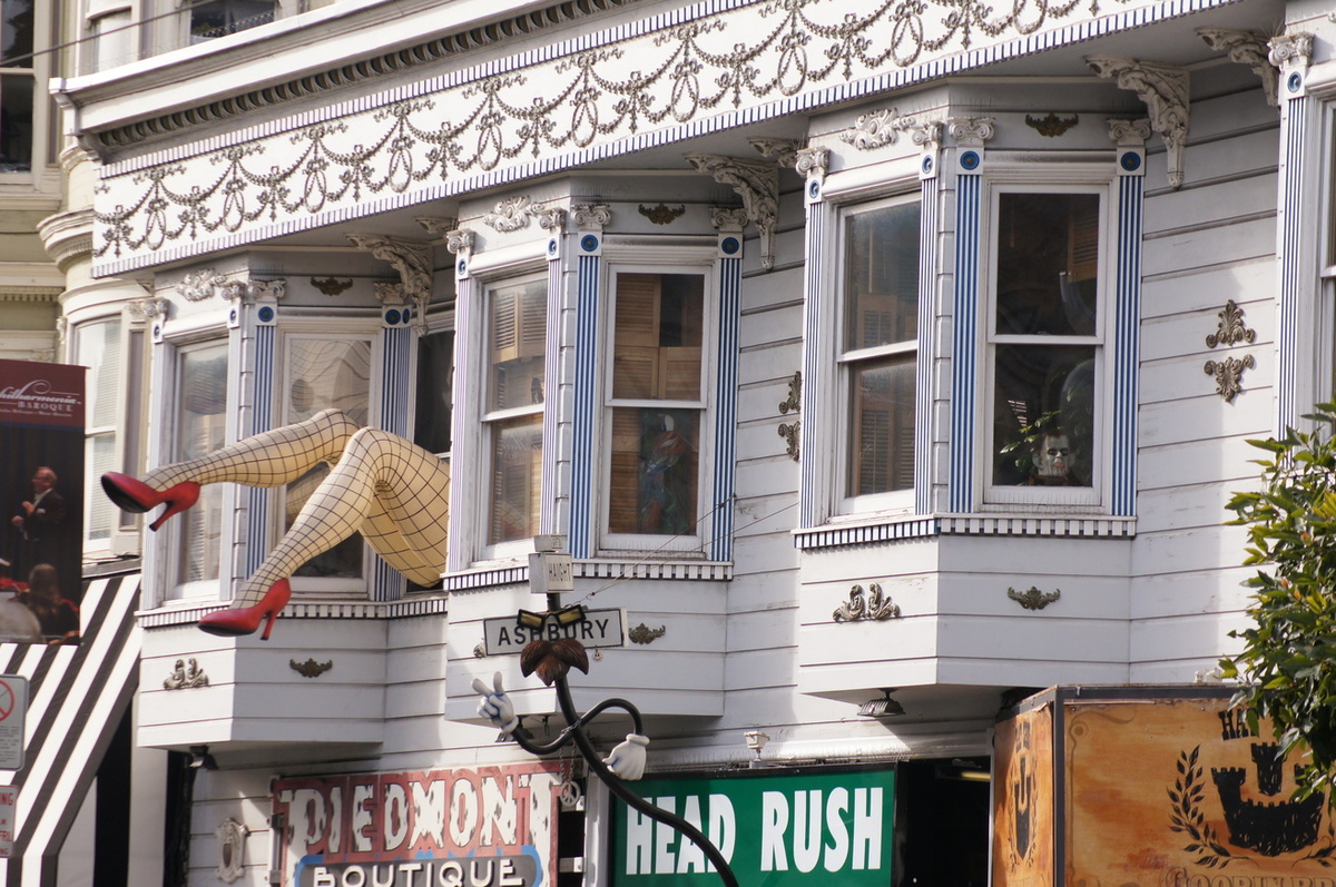 An image of a house with a large pair of fishnet-clad legs hanging out of the window.