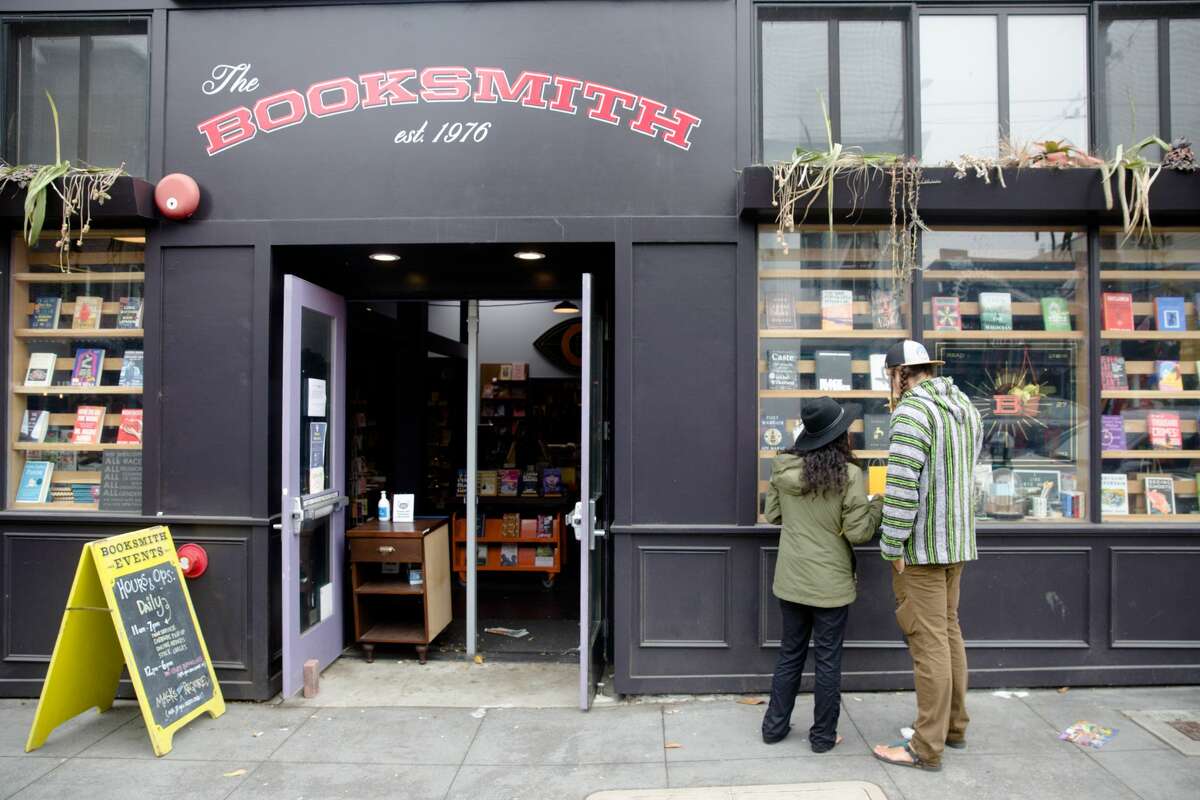 The front of a bookstore called “The Booksmith”. Two people stand outside of it.