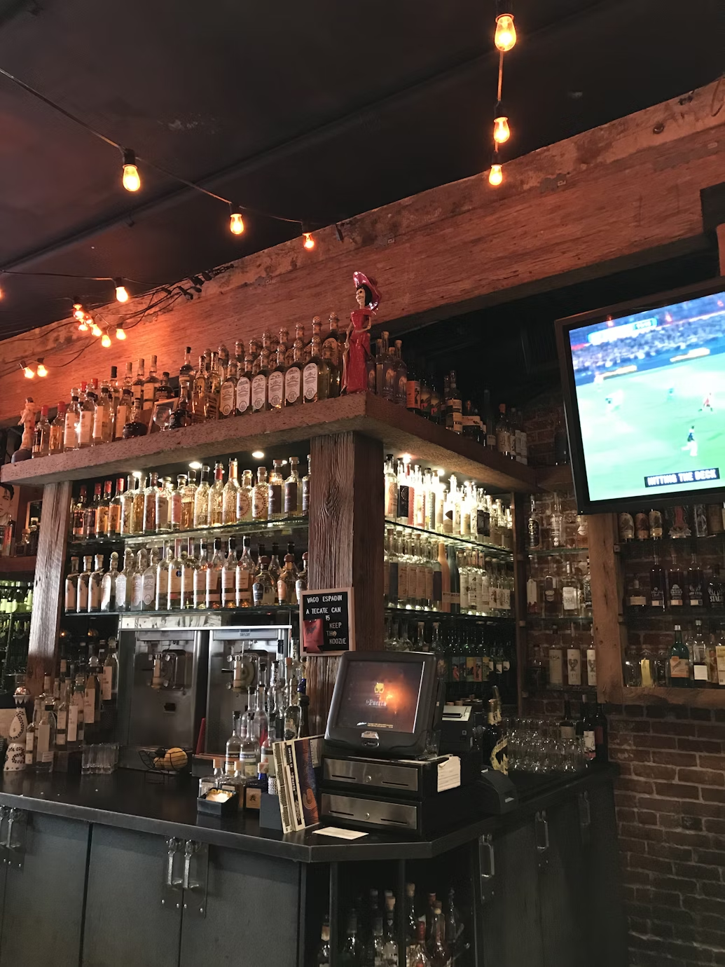 A flat screen TV playing soccer next to a bar.