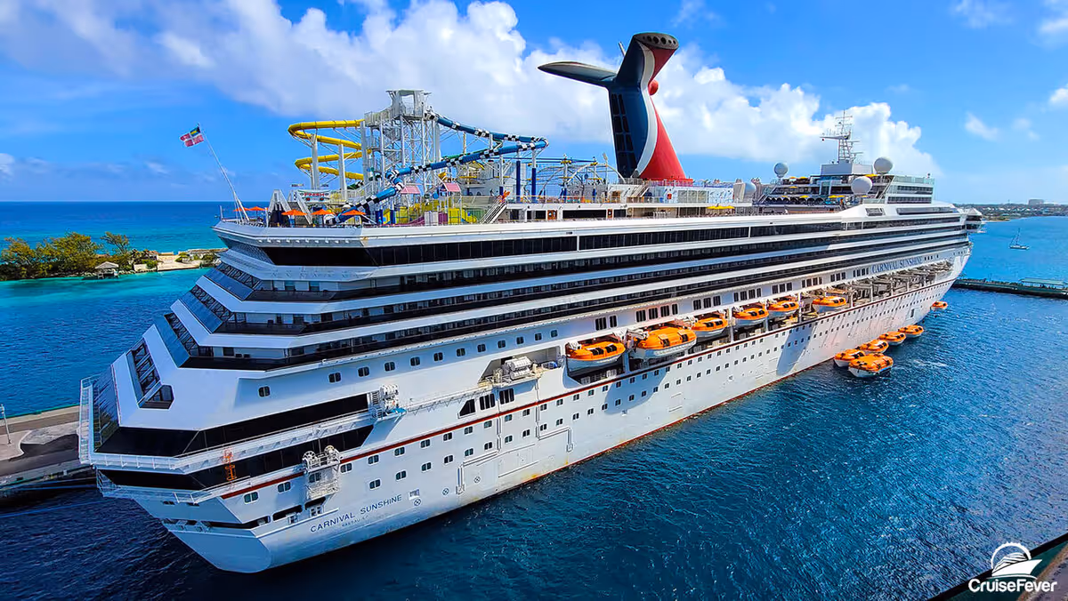 A large Carnival Cruise cruise ship with a water slide on the top deck.