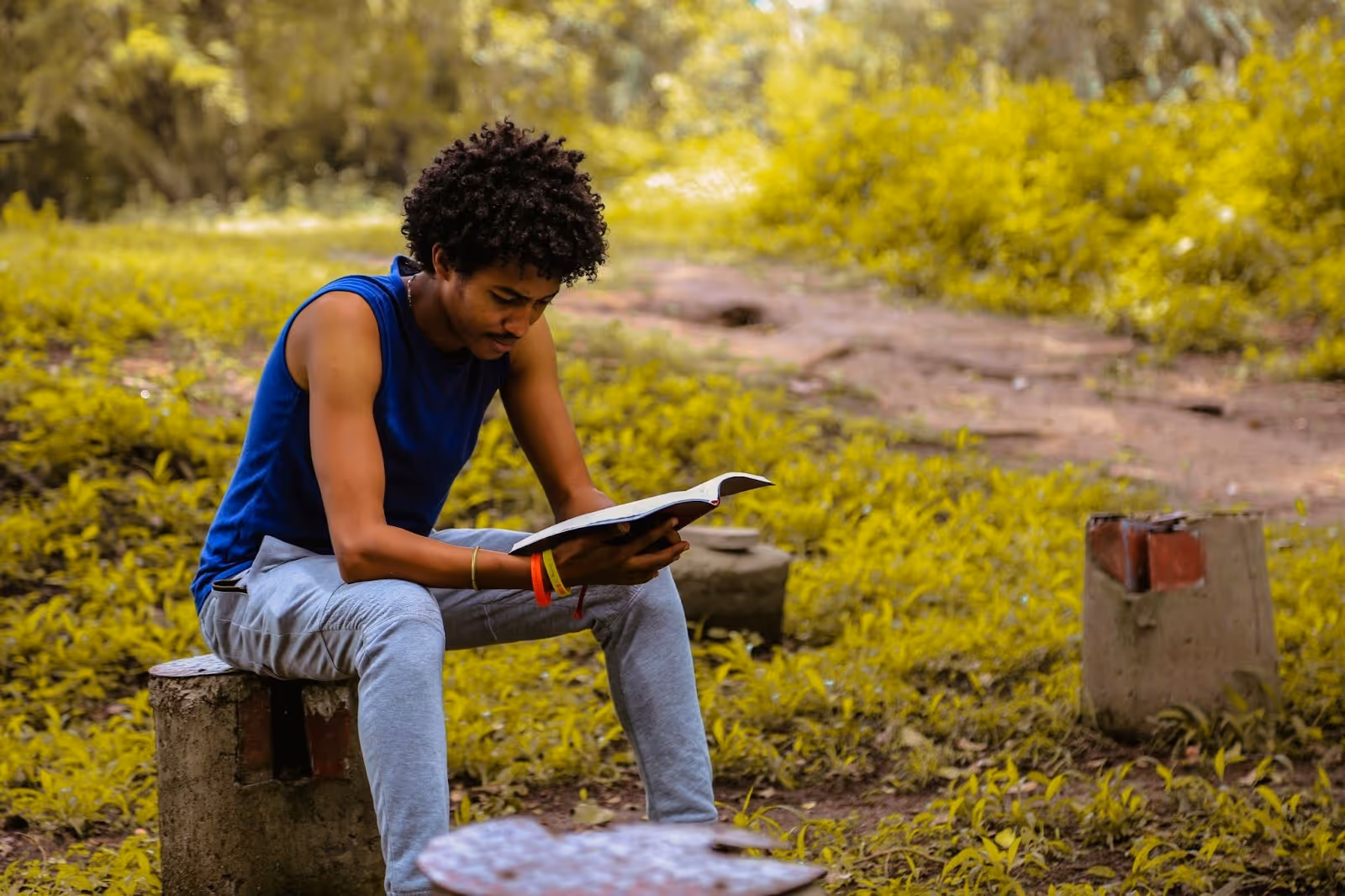 young man sitting in nature and reading for his own self betterment