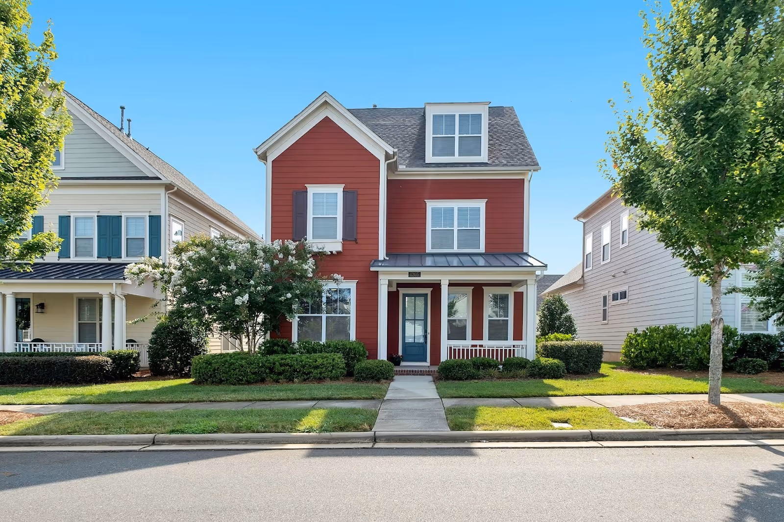 beautiful red two-story starter home in a quaint suburban neighborhood on a tree-lined street