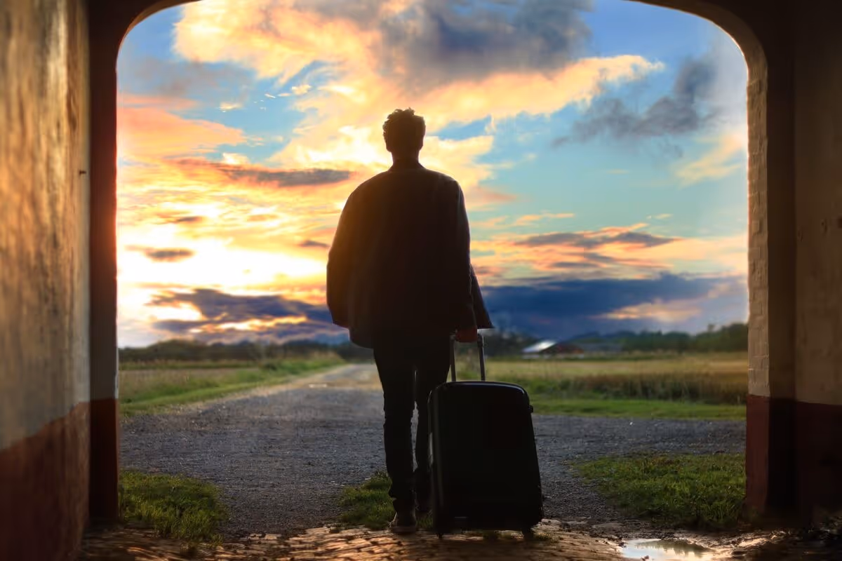 young man with a suitcase walking off into the sunset