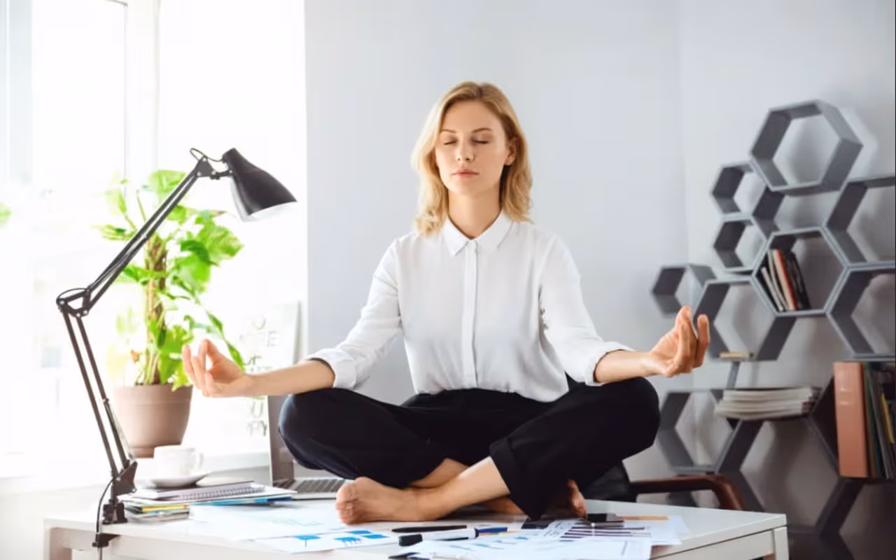 woman doing a meditation pose on her desk