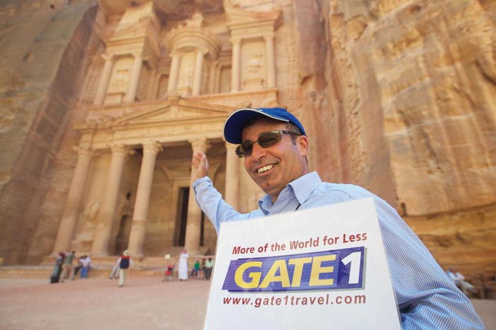 experienced tour manager holding Gate1 Travel sign in front of Petra