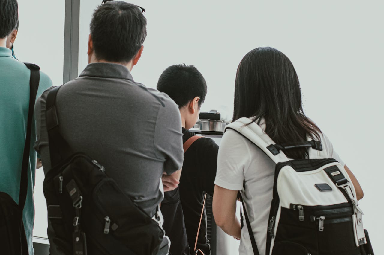 travelers wearing backpacks waiting in a TSA line