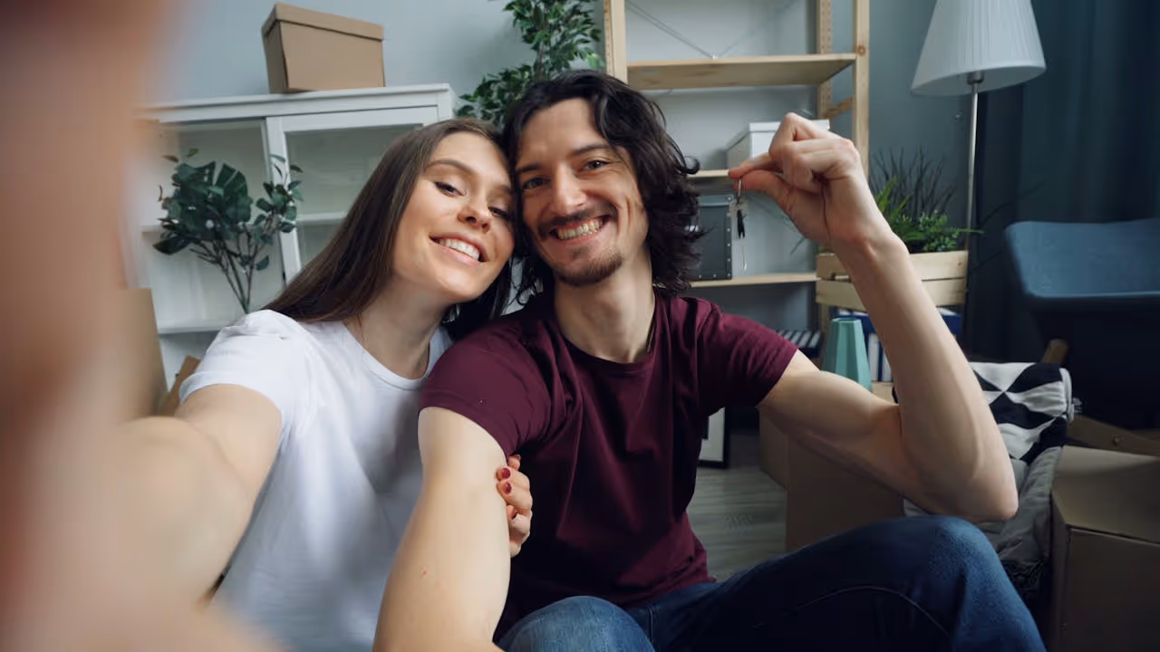 20something first time homeowners take a proud selfie with the keys to their first house