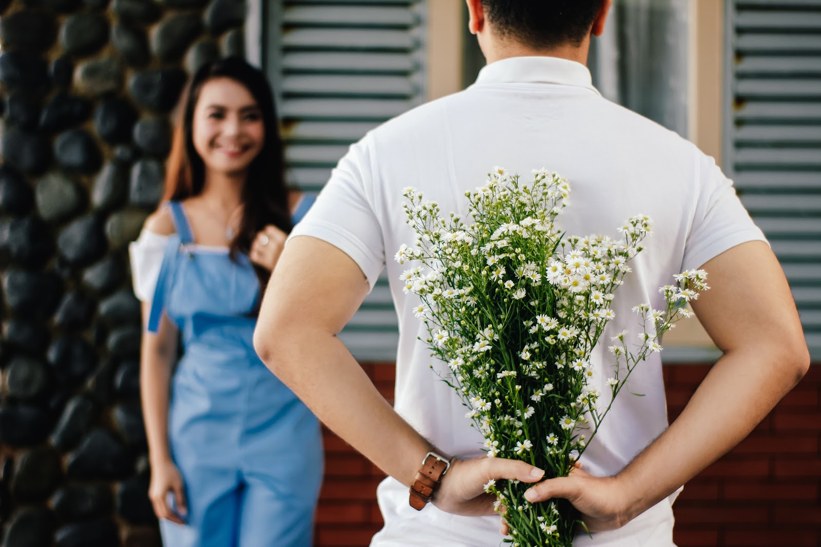 Man holding baby's breath behind his back for a woman that is blurred