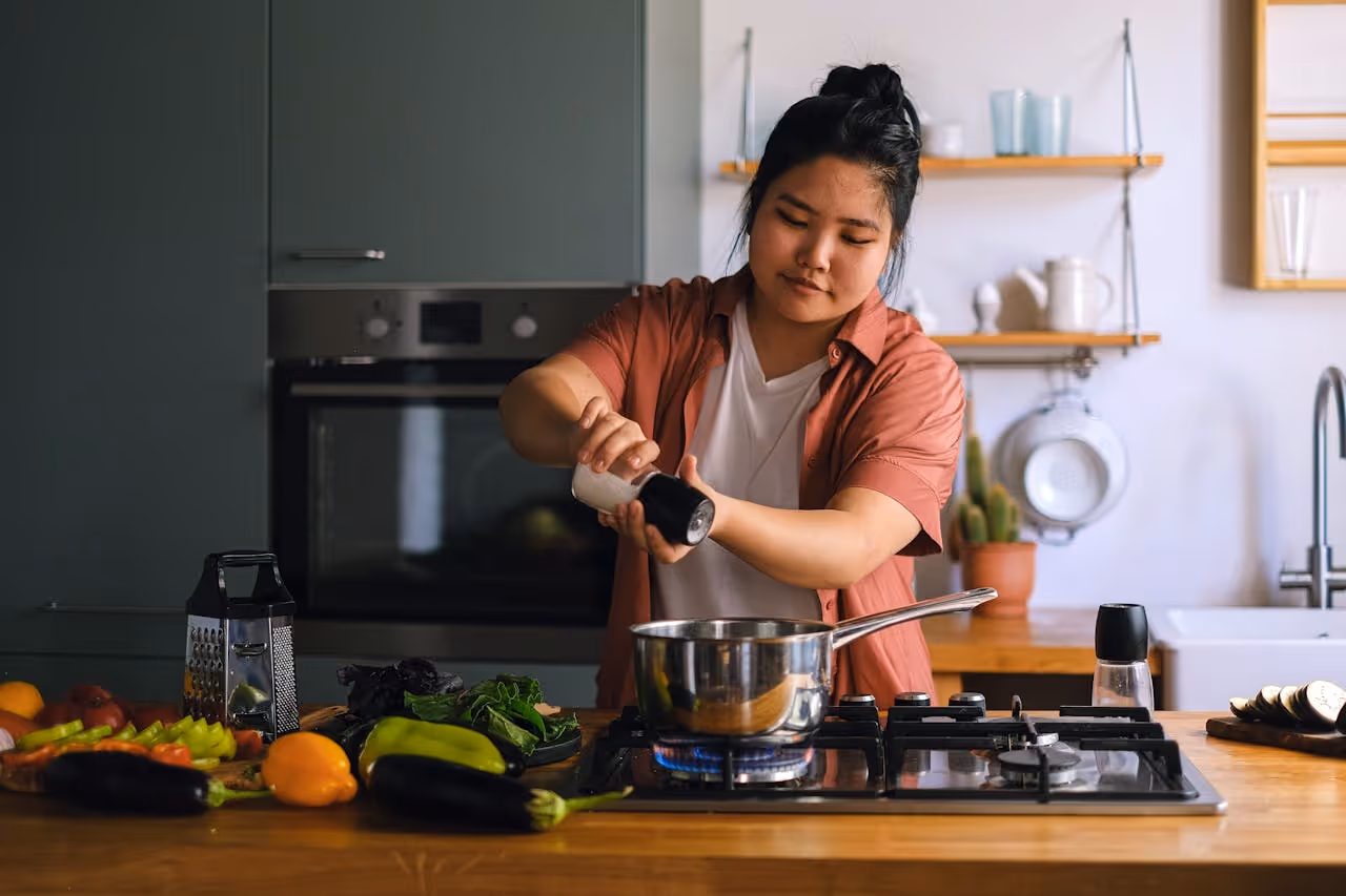 20something woman cooking dinner in her first apartment