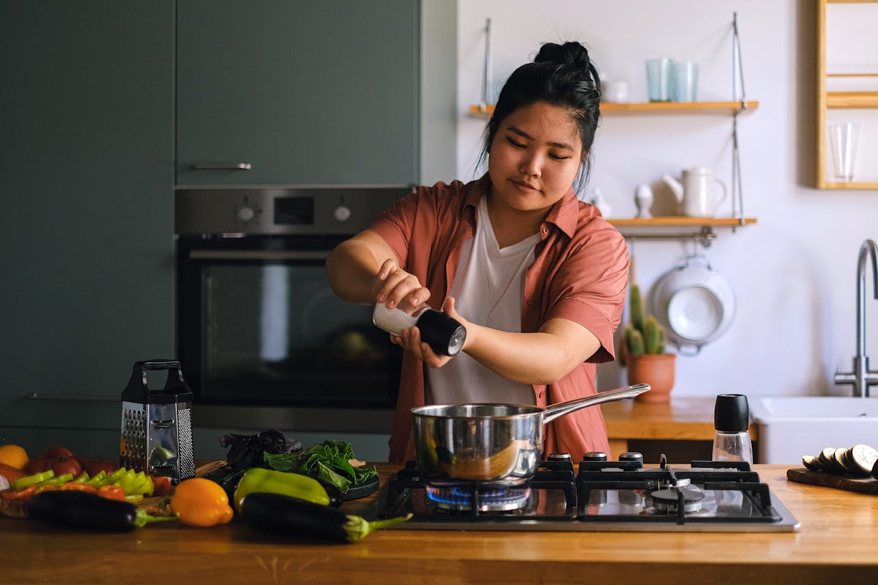 20something woman cooking dinner in her first apartment