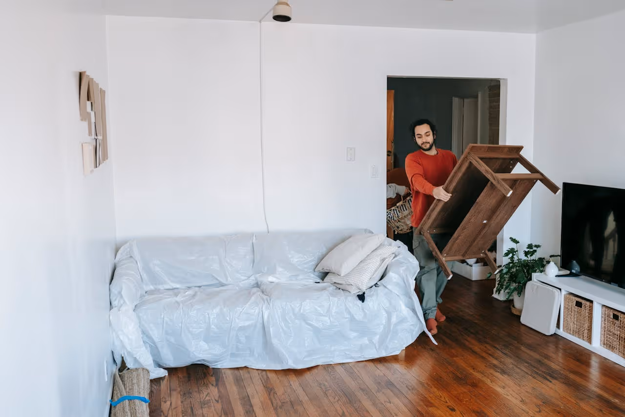 20something carrying a coffee table into the living room of his new apartment on moving day