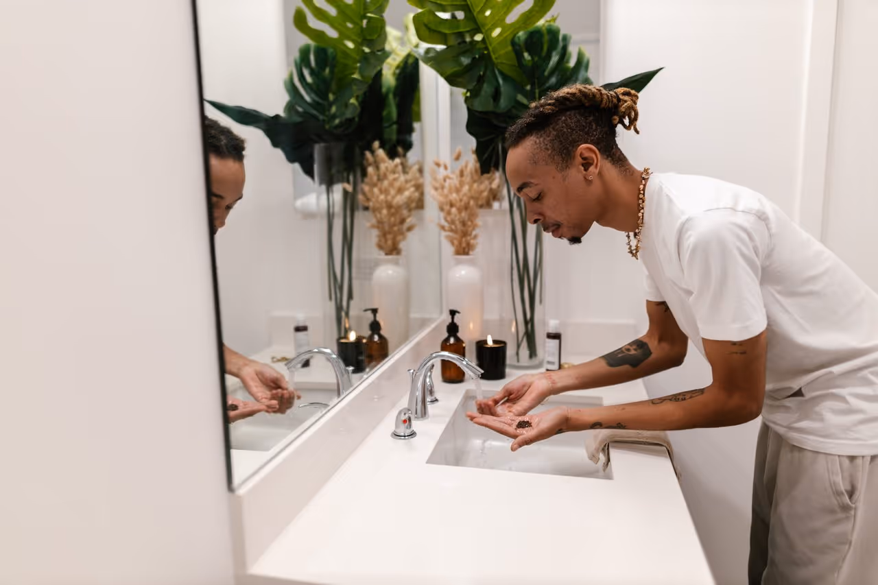 man washing his face in the sparkling clean bathroom of his first apartment