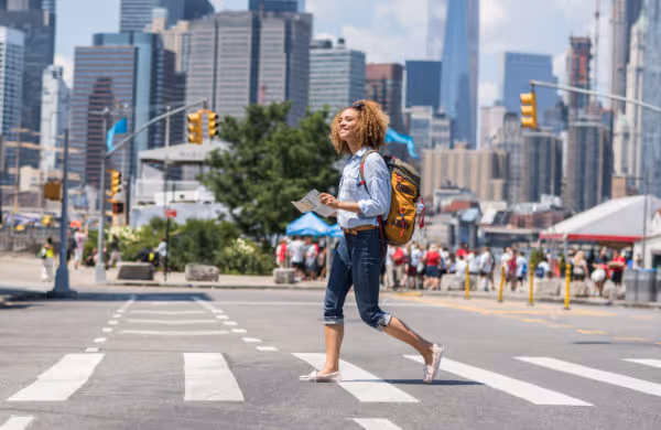woman marching across a crosswalk, map in hand, in New York City