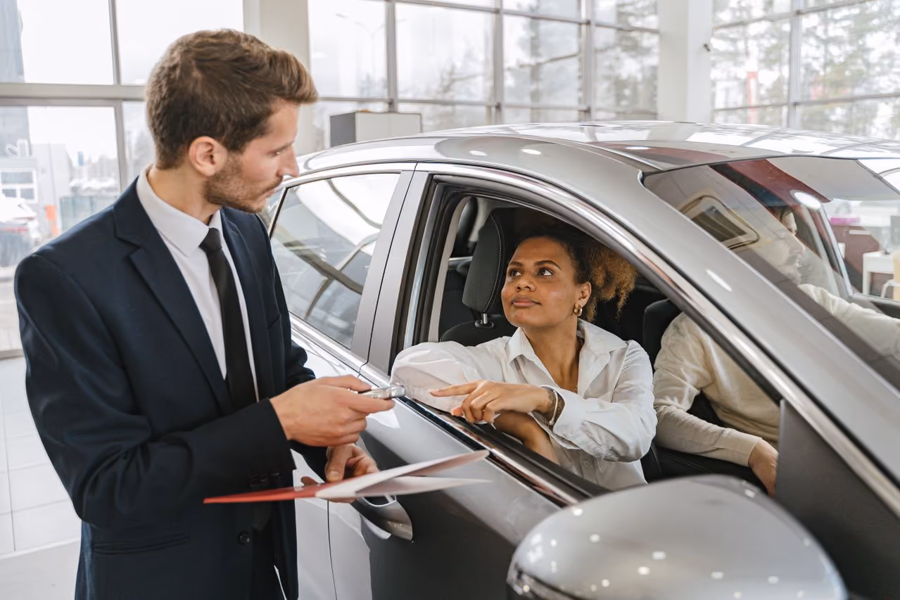 woman in a new car talking to a salesman, deciding if gap insurance is worth adding to her car purchase