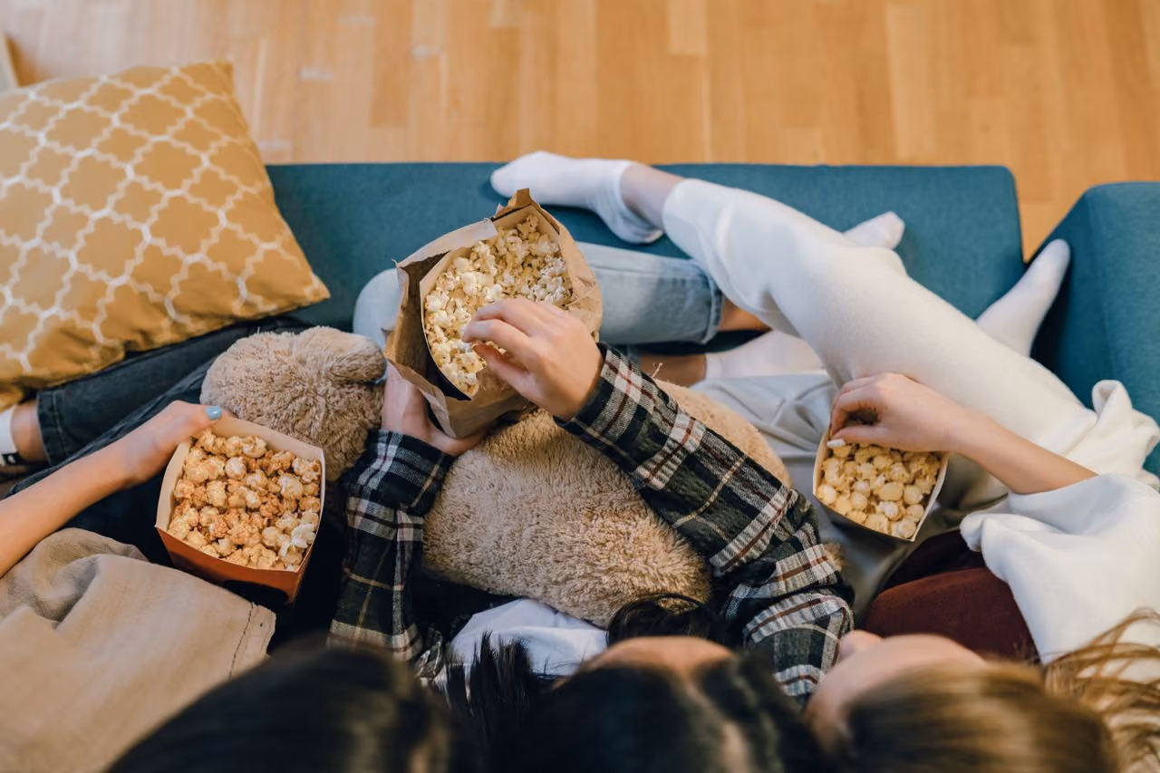 three college girls gathered around munching on a popcorn snack