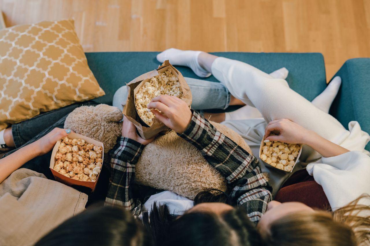 three college girls gathered around munching on a popcorn snack