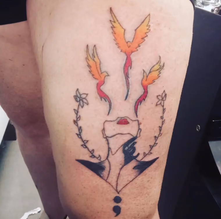 semicolon tattoo with a line art portrait of a woman's upturned face over it from which three phoenix are rising