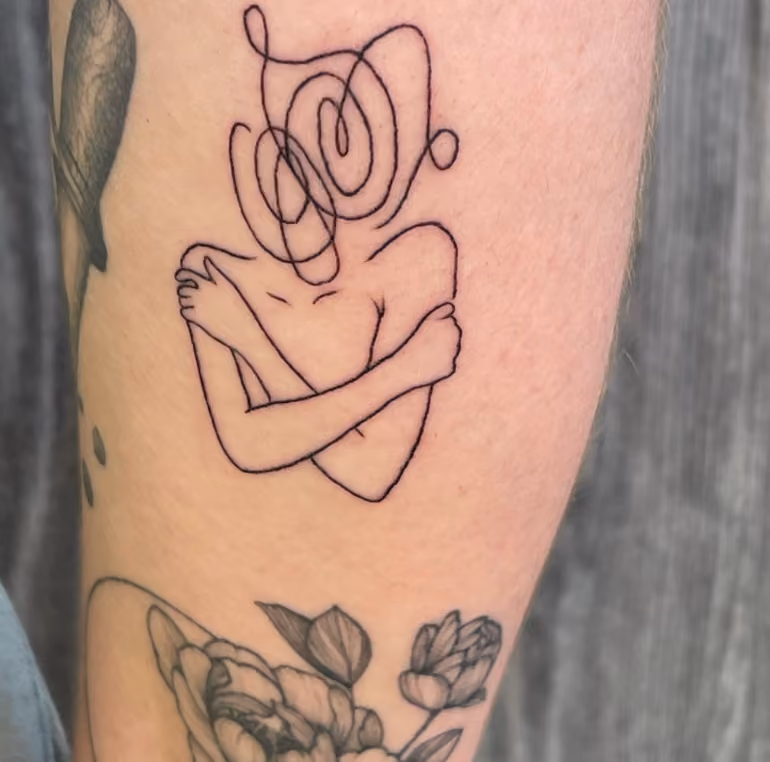 line drawing tattoo of a figure hugging themself with the head replaced by a confused squiggle