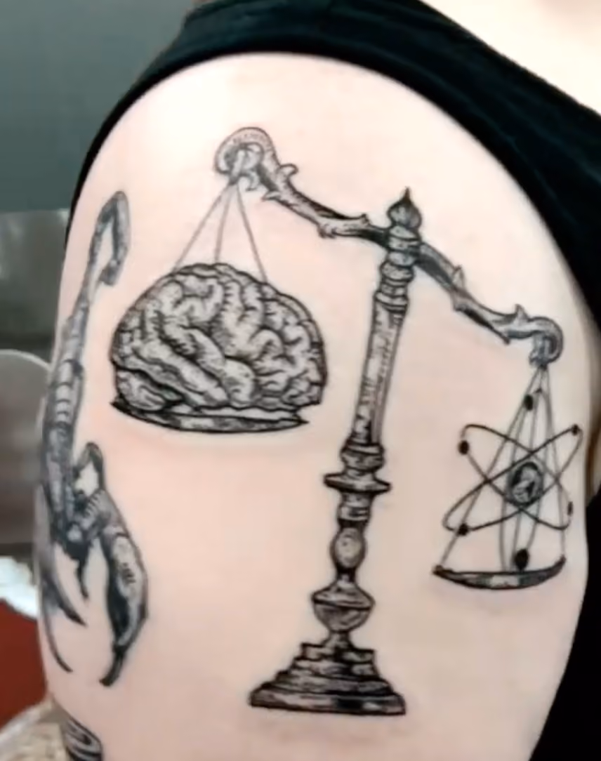 tattoo featuring a human brain and a diagram of an atom on a scale representing mind over matter