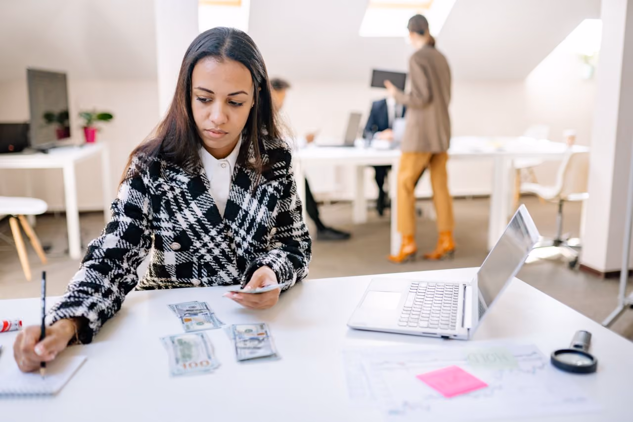 young woman with financial information spread out in front of her deciding if a Roth IRA is worth it