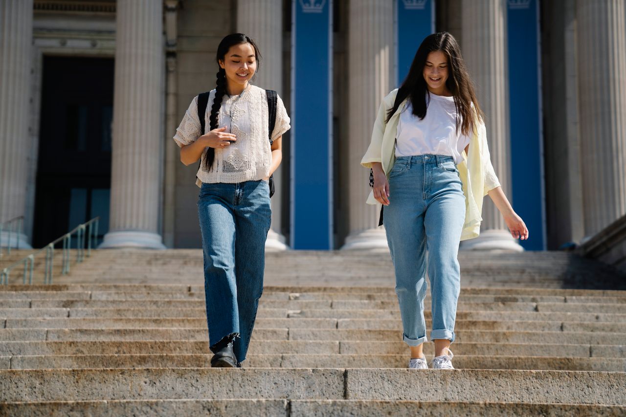 two college students smiling on their campus because they knew what to do the summer before college to get ready