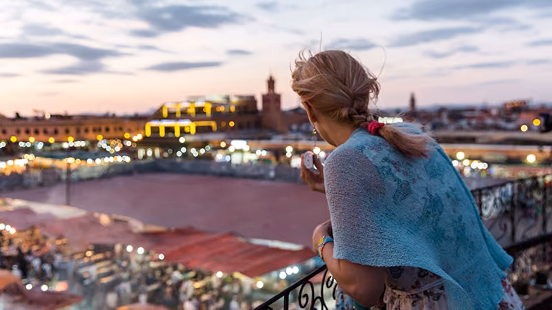 woman taking in a rooftop view of the city at night on her first solo trip