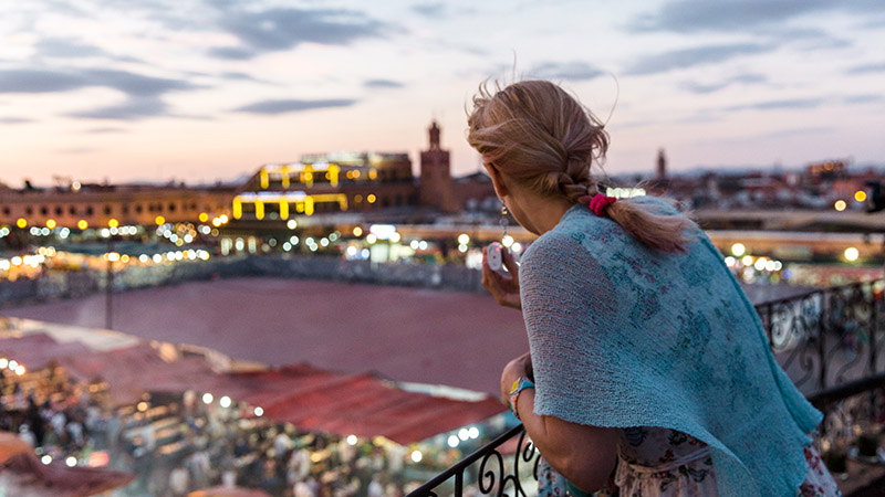woman taking in a rooftop view of the city at night on her first solo trip