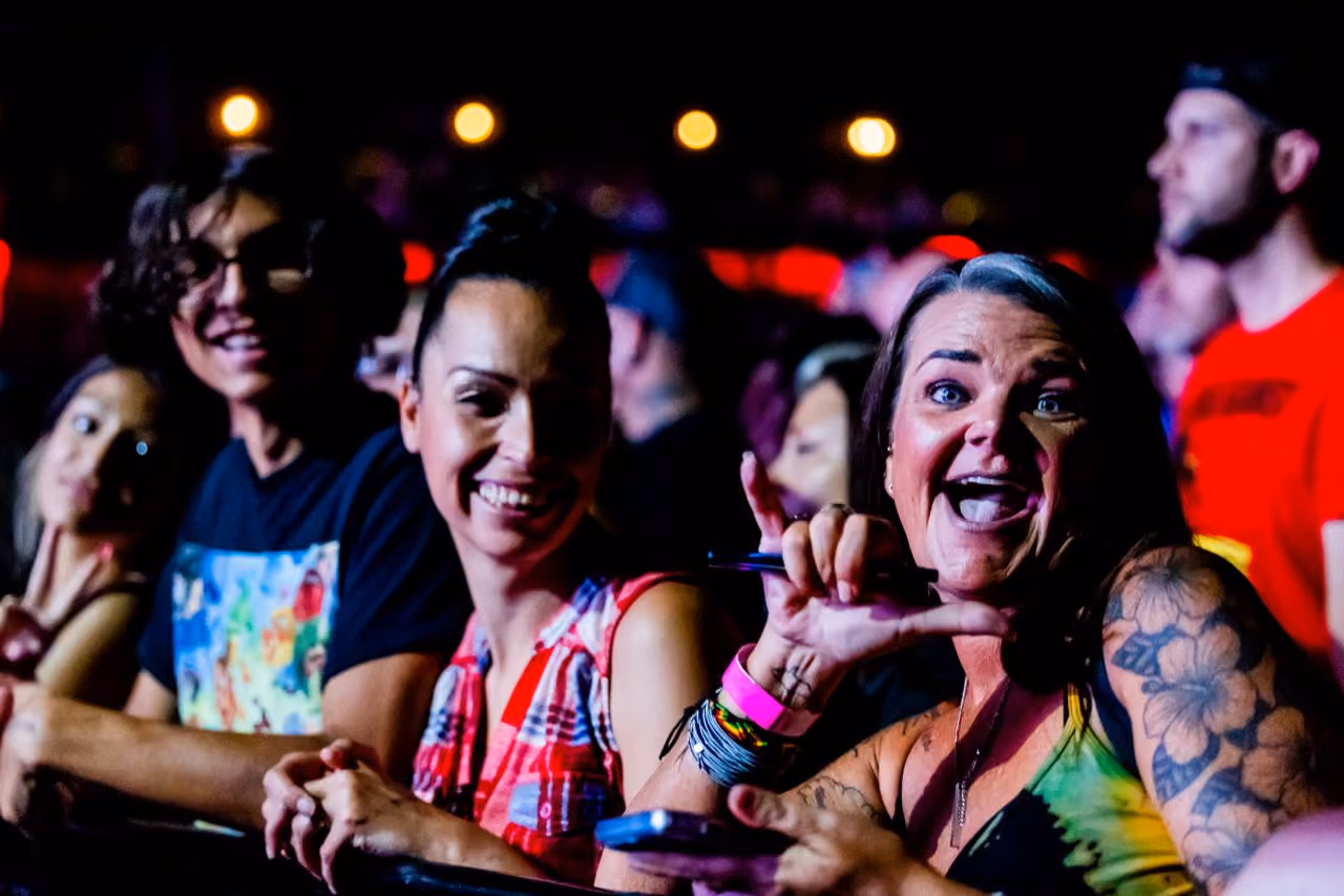 group of concert goers ages ranging from early 20s to late 40s front row for a set at a music festival having a great time