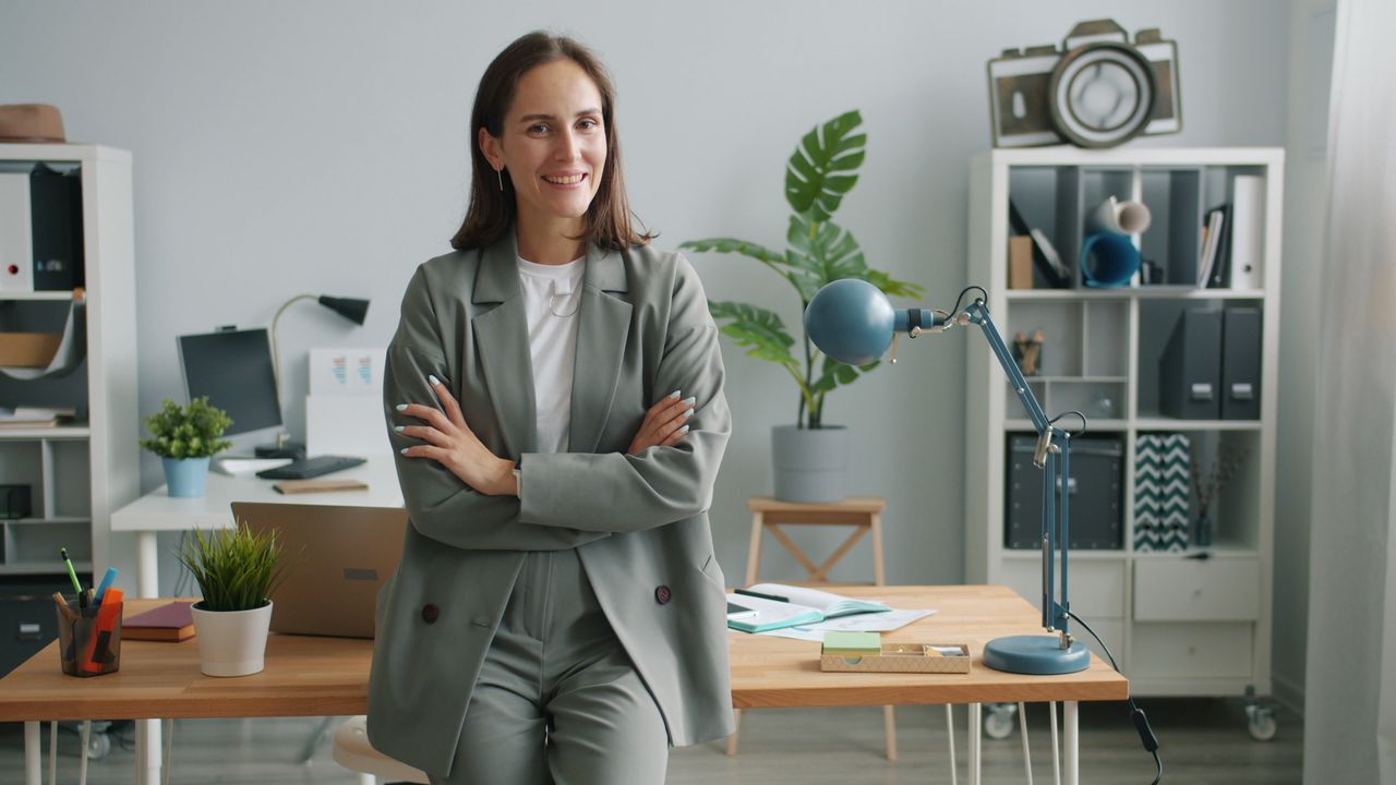 woman leaning against a desk in a bright, open office after successfully switching careers