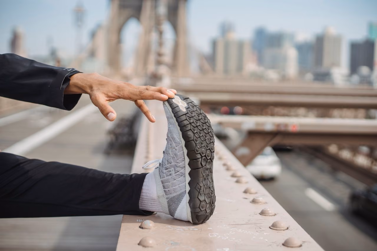runner wearing Hoka alternatives that are a better fit for his lifestyle stretching before a jog across the Brooklyn bridge