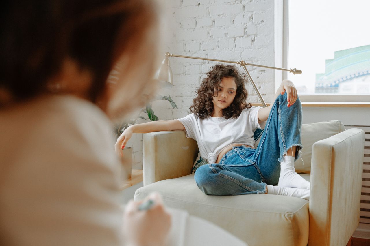 young woman in a therapy session, looking distracted wondering if therapy is worth it as her provider speaks