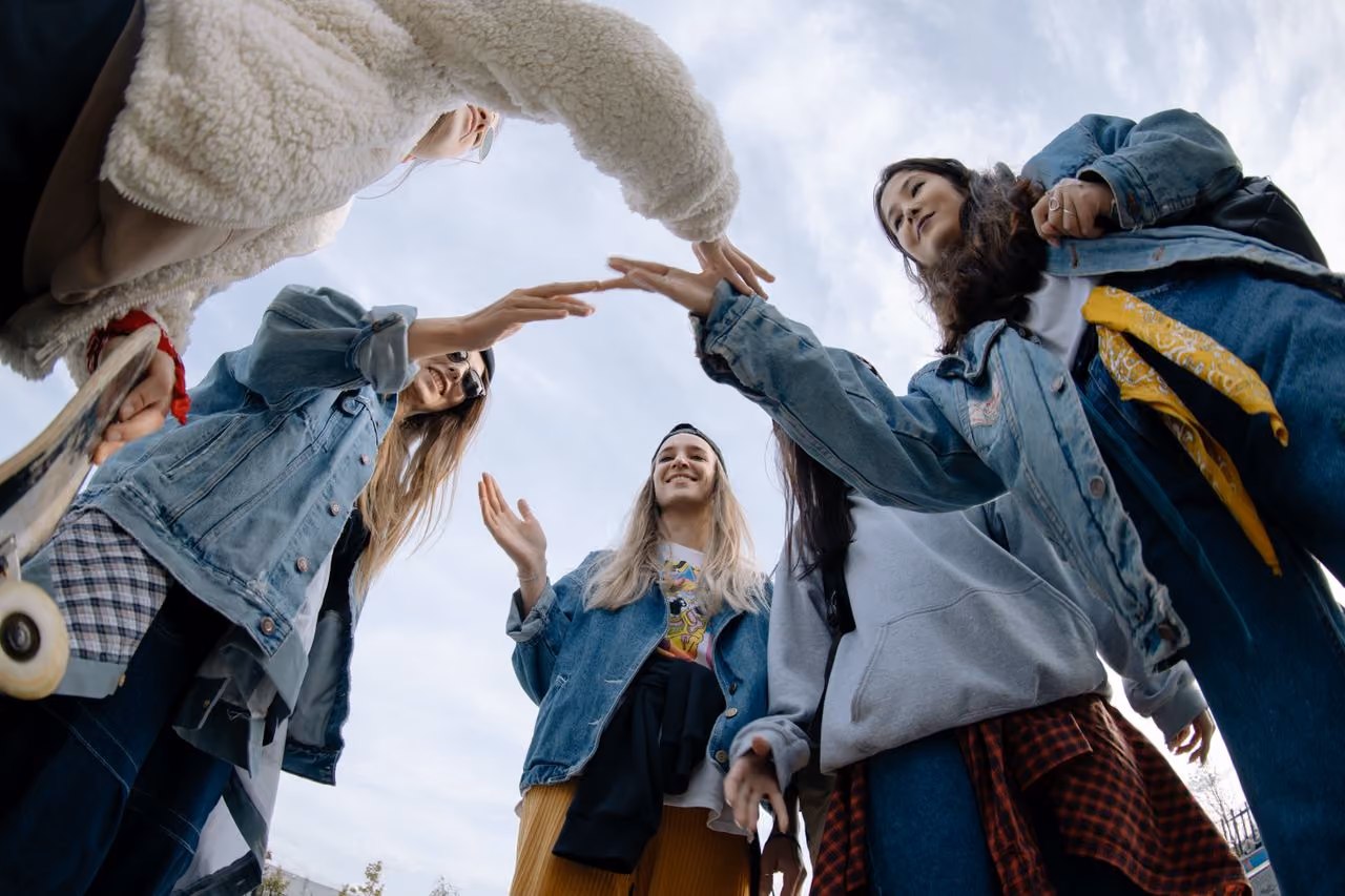 group of young people all wearing trendy denim jackets doing a handshake and finding camaraderie as they learn to express and understand themsevles