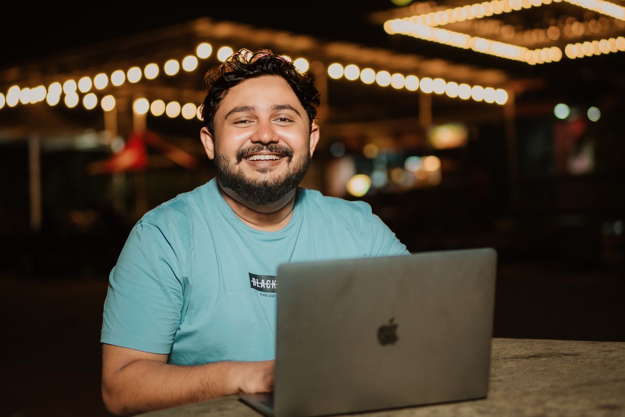 young professional sitting in front of an open laptop, doing remote work even though he's out at a restaurant