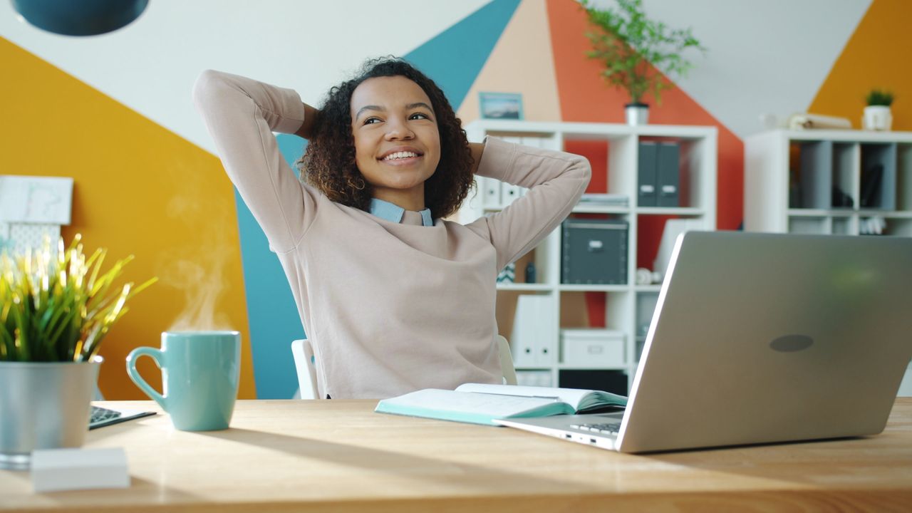 young woman leaning back at her desk looking relaxed, secure that she's established professional boundaries that will protect her personal life now when things are normal and in the future in case things get chaotic