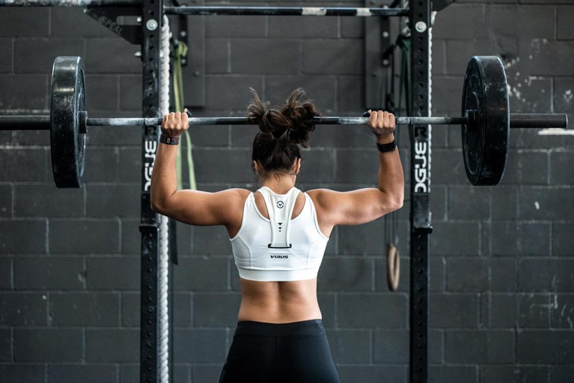 Strong woman lifting weights in a gym, showcasing how regular exercise reduces anxiety and boosts confidence