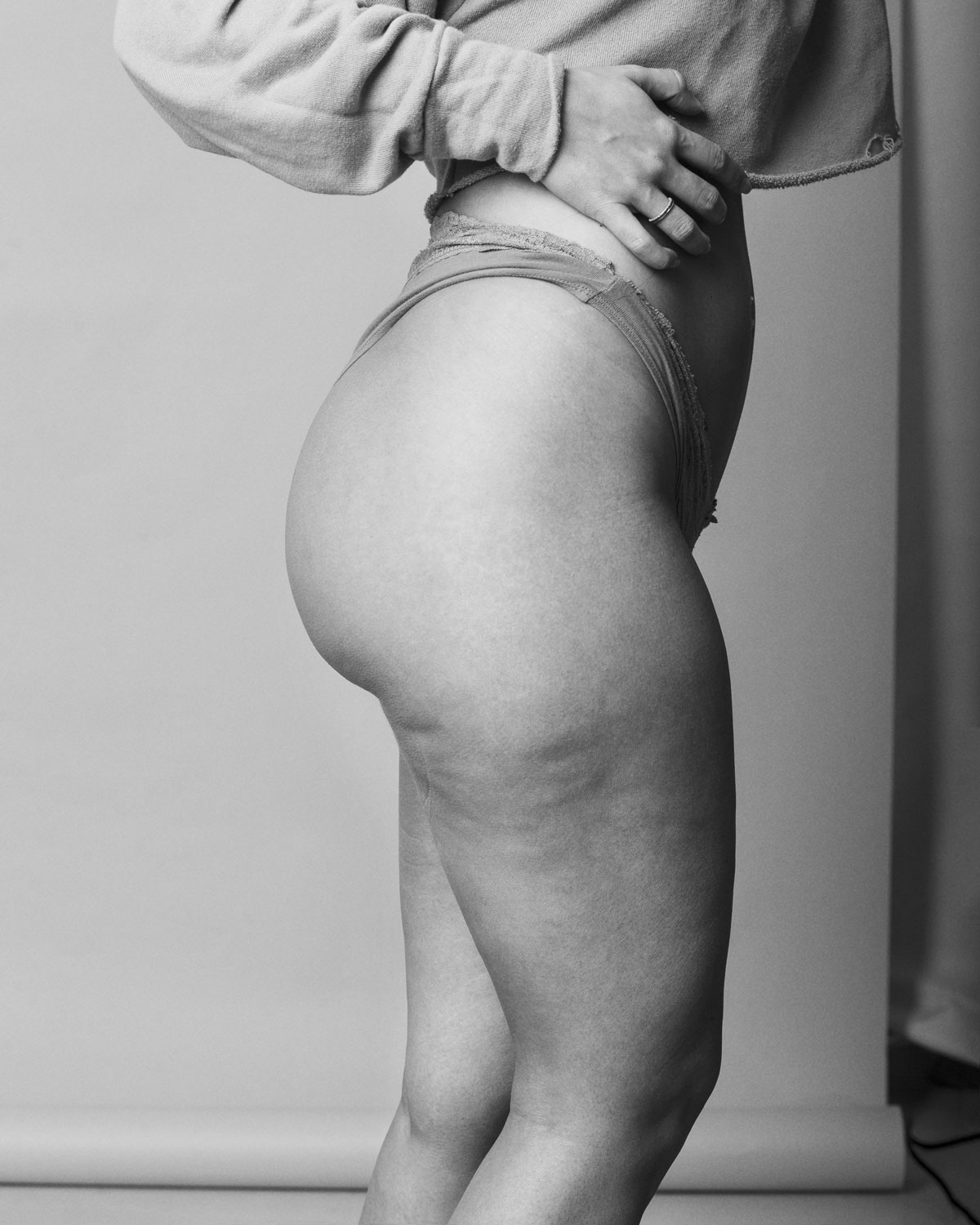 Empowering black and white photo of Gabriela embracing her body with visible cellulite and curves