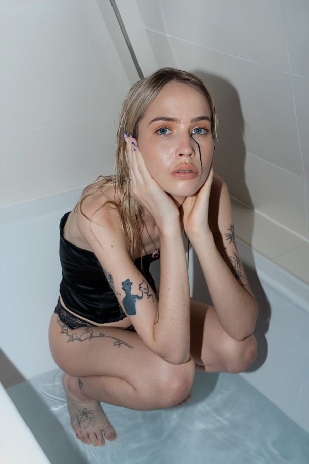 Zoe Waechter in a bathtub with running eyeshadow, capturing vulnerability and artistic emotion