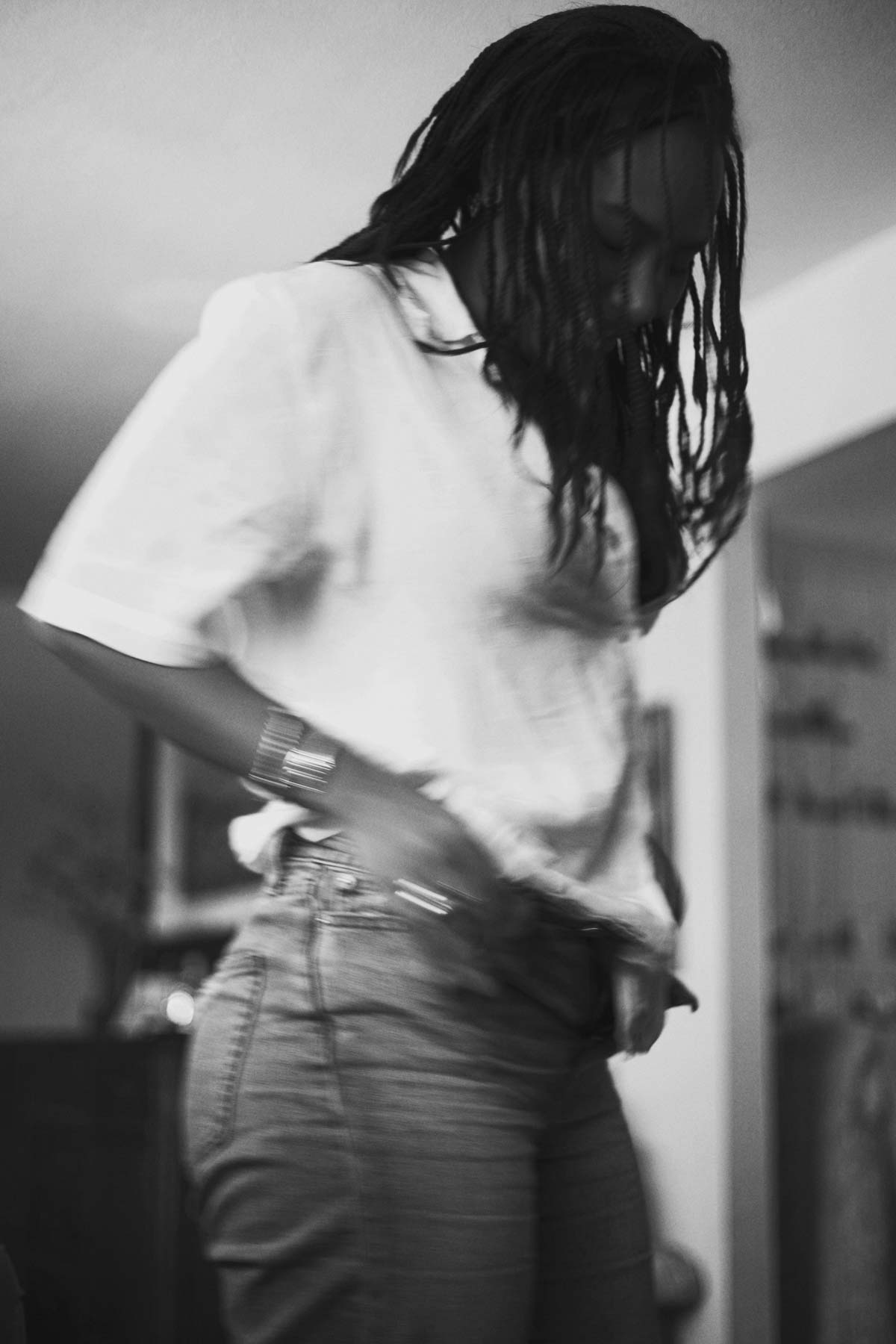 Black and white photo of a Black woman playing for her jeans, showcasing her natural beauty and confidence.