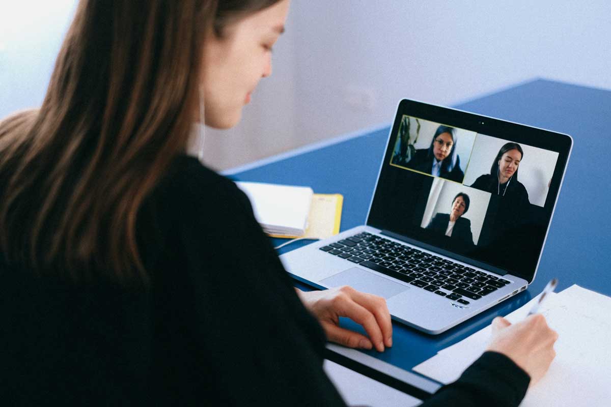 Young woman participating in a Zoom meeting on her laptop, looking focused while working from home.