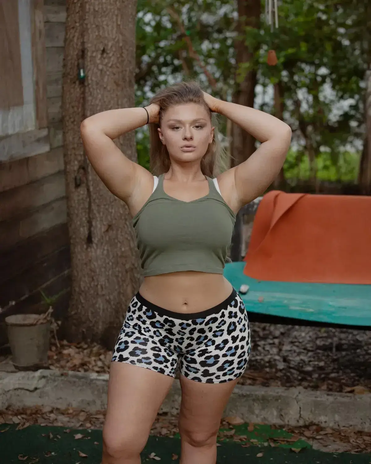 Confident woman embracing her natural curves outdoors in a green crop top and printed shorts