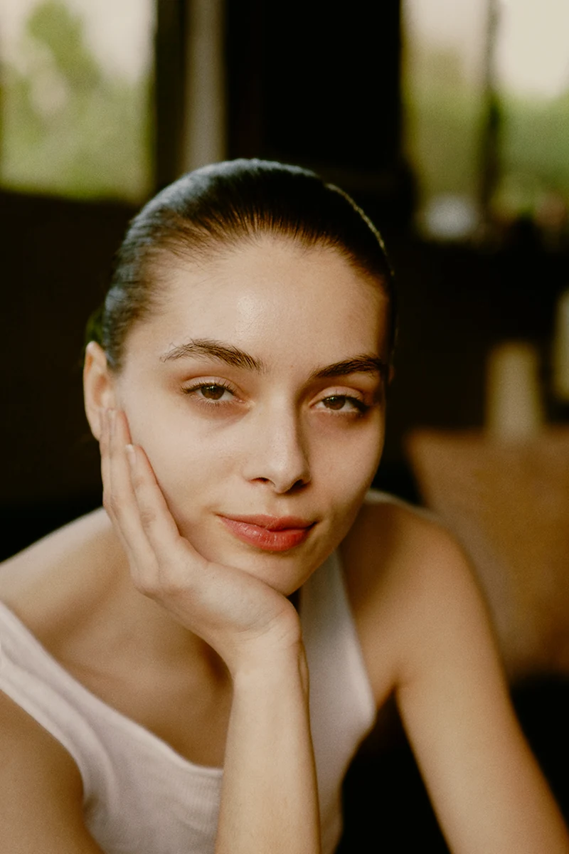 Color portrait of a young Latina woman with slicked-back hair, no makeup, wearing a tank top, shot in natural light, highlighting her natural beauty.
