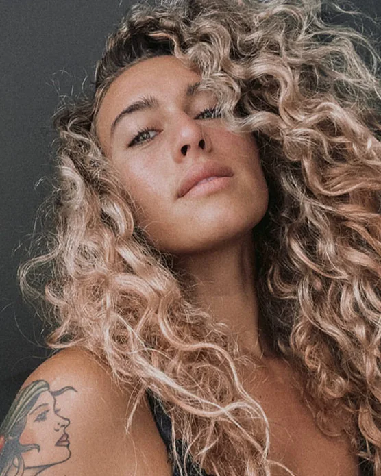 Close-up of Bailey Rushlow with blue eyes and blonde curly hair, highlighting her natural beauty and radiant skin