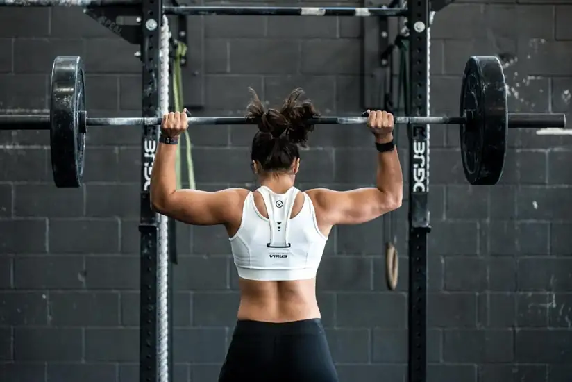 Strong woman lifting weights in a gym, showcasing how regular exercise reduces anxiety and boosts confidence