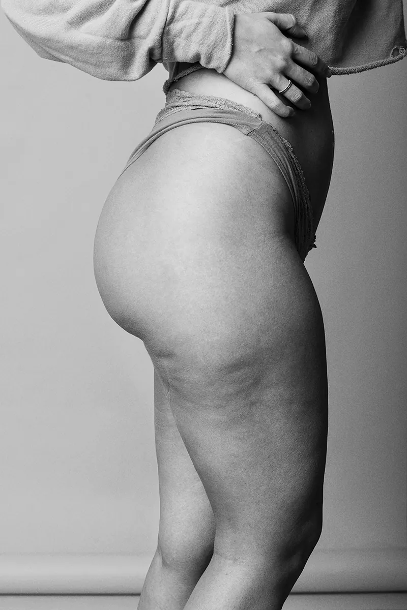 Empowering black and white photo of Gabriela embracing her body with visible cellulite and curves