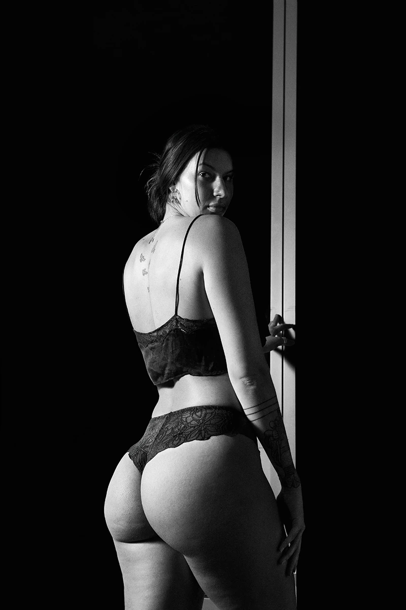 Black and white photo of Willow Johnson’s back, showing tattoo, natural curves, and cellulite with no makeup